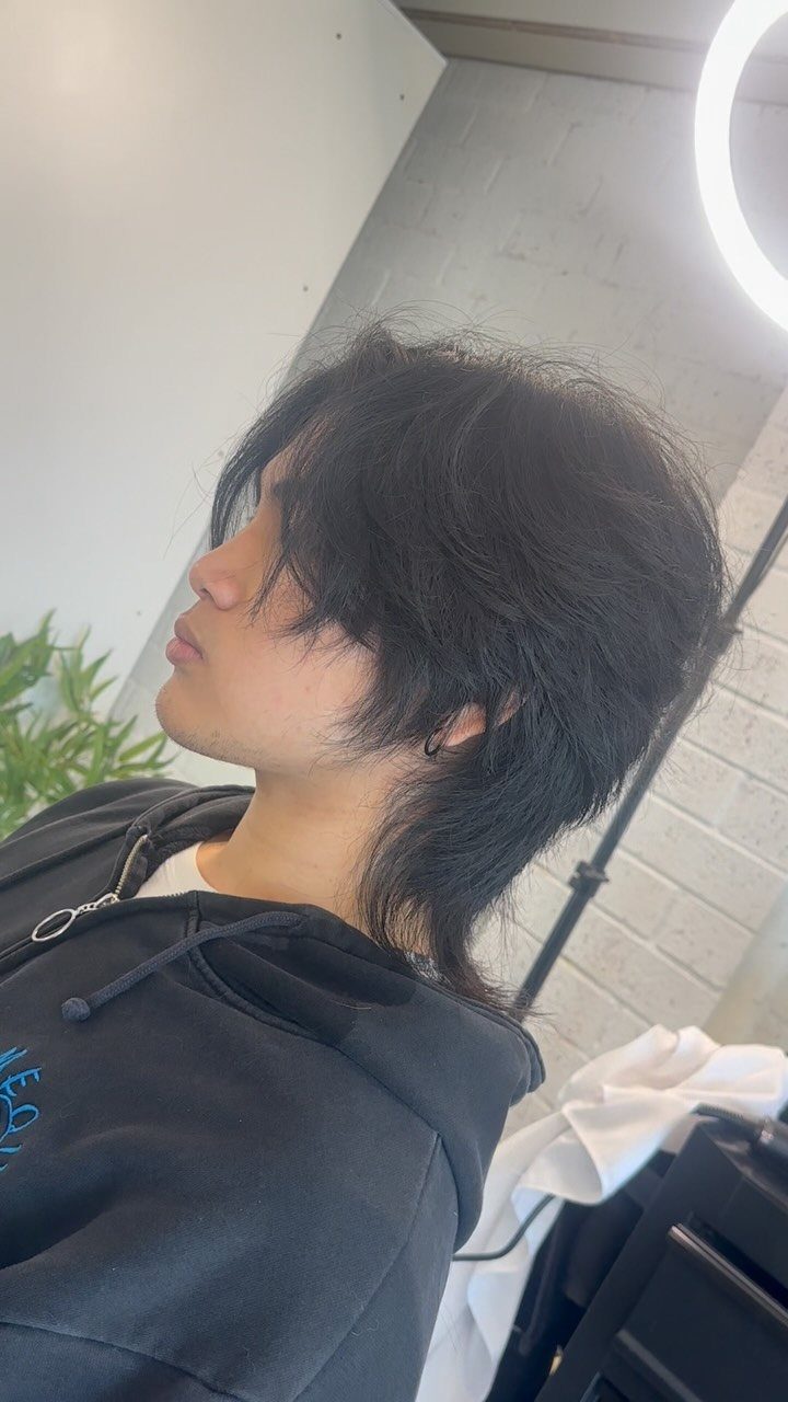Young man with a shaggy black long wolf cut hairstyle and black hoodie.