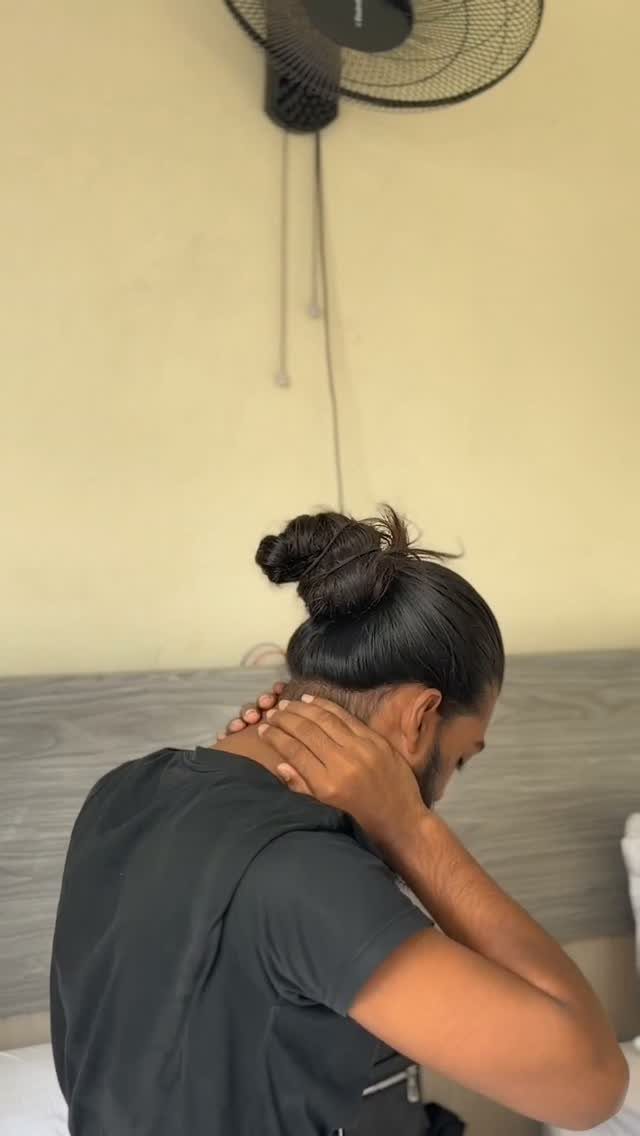 Man with dark hair tied into a man bun wearing a black t-shirt.