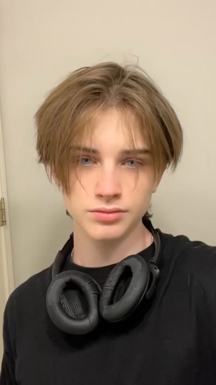 Young man with sleek straight light brown hair parted in the middle.