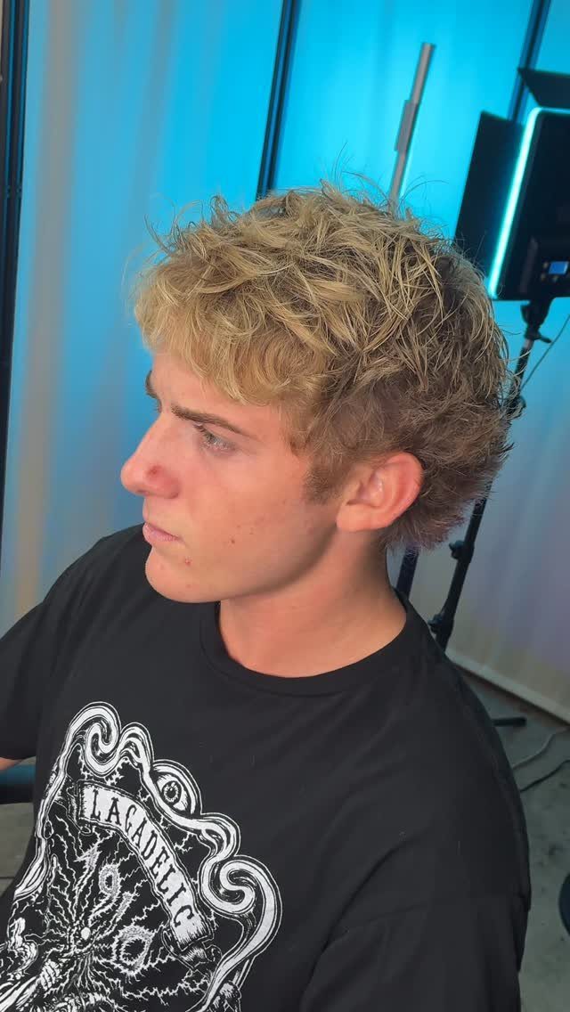 Young man with short blonde wavy hair styled in textured layers side profile