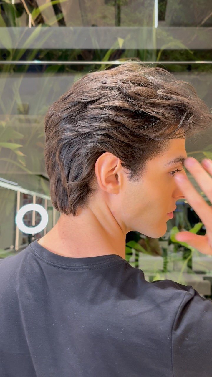 Young man with wavy brown hair styled in a voluminous bro flow haircut.