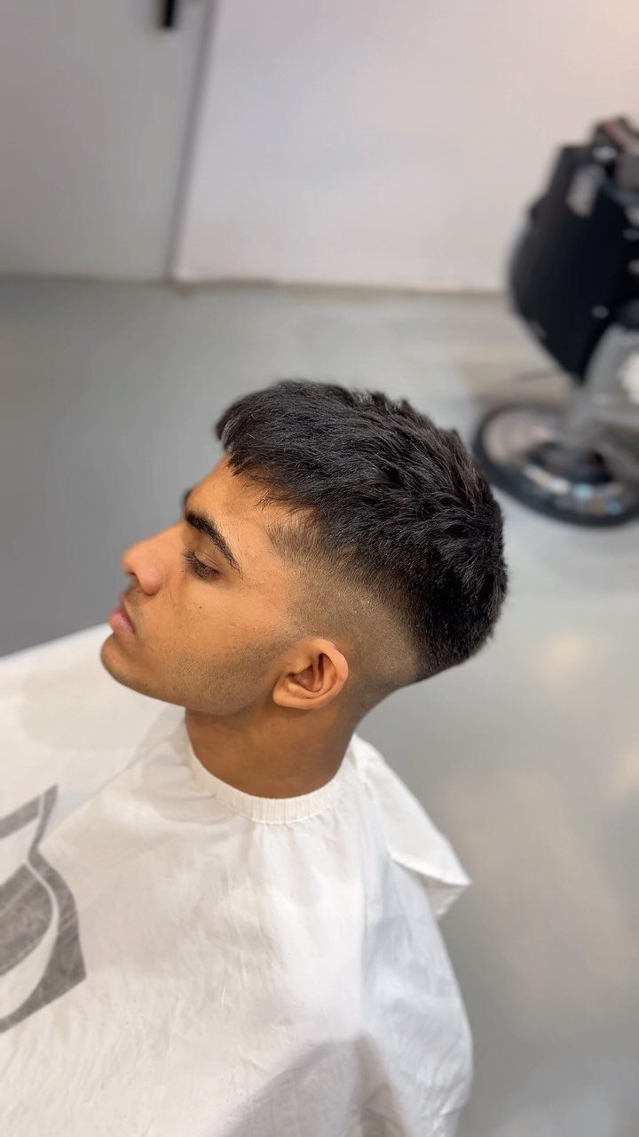 Young man with a skin fade haircut and textured short top in a salon