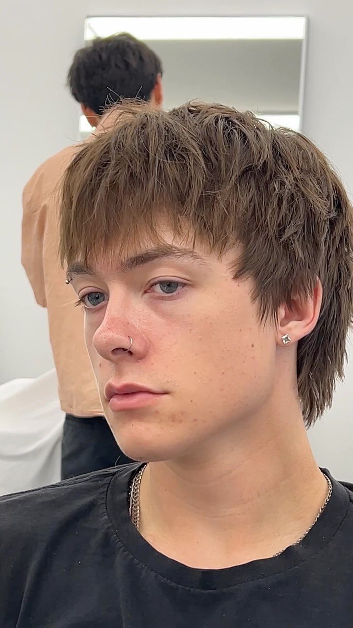 Young man with a textured straight brown haircut and bangs in a salon.