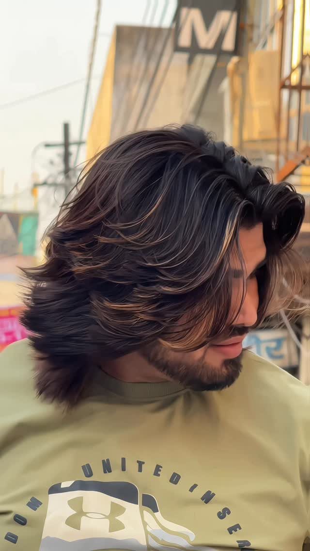 Man with long brown hair and highlights paired with a groomed beard.