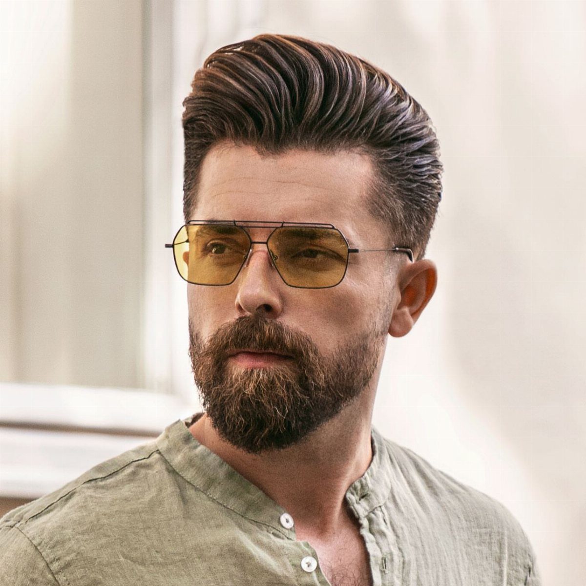 Man with a high volume pompadour hairstyle and a full groomed brown beard.