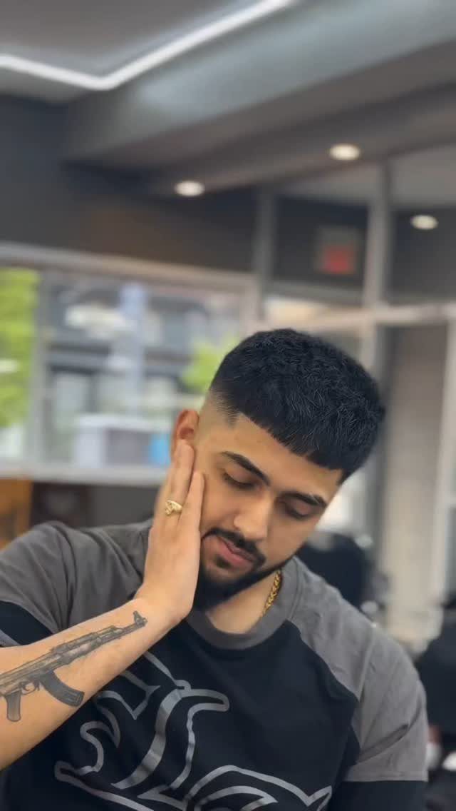 Man with a textured crop haircut and groomed beard posing indoors.