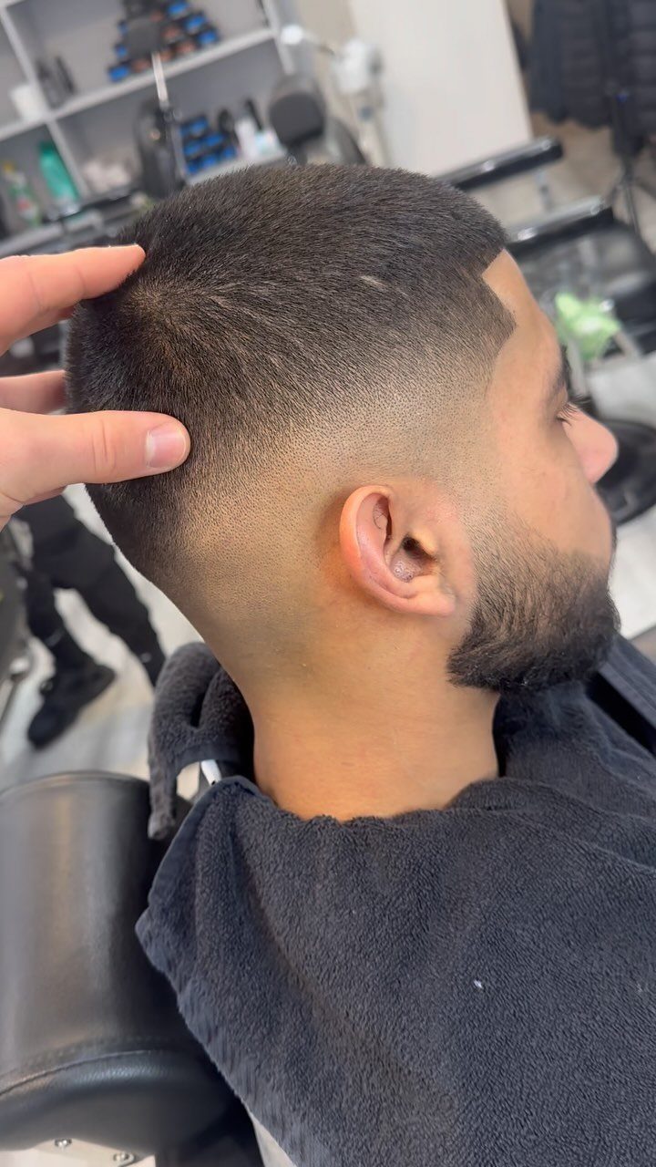 Man with a short buzz cut and high skin fade in a barbershop.