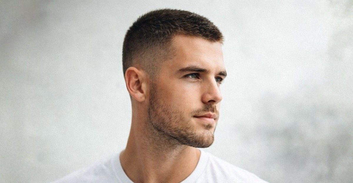Man with a short crew cut hairstyle and faded sides wearing a white shirt.