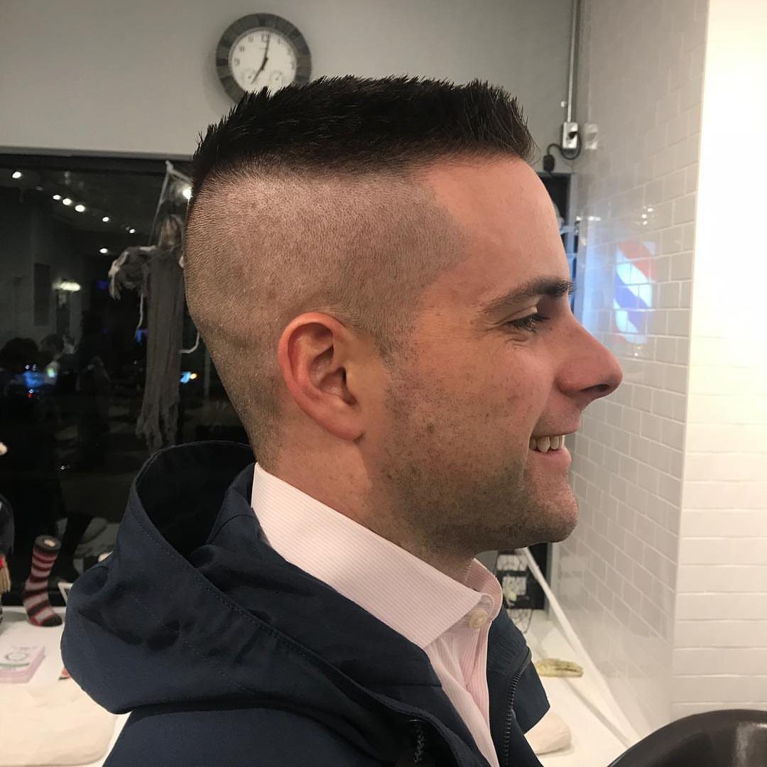 Man with a high and tight haircut smiling in a barbershop setting.