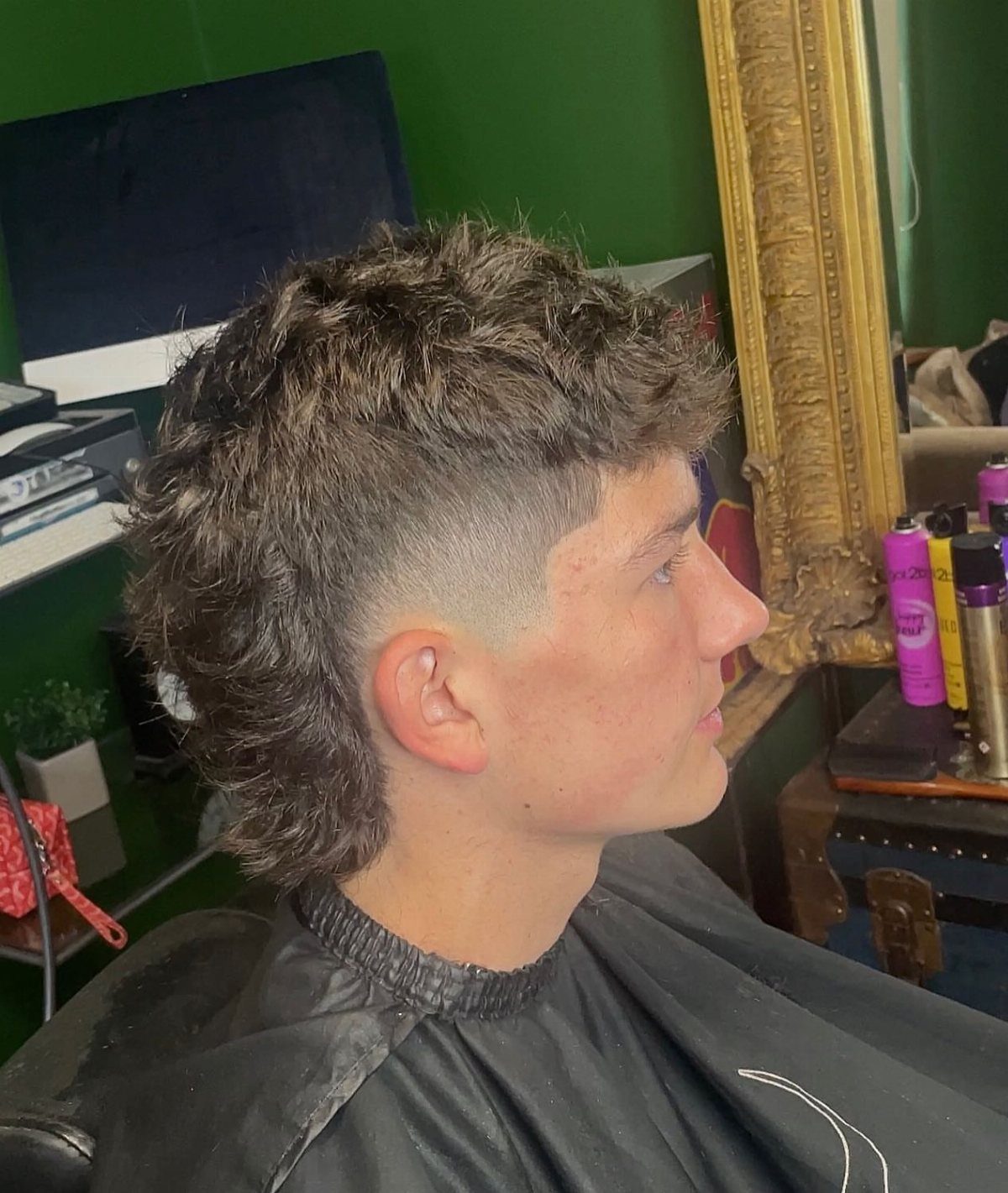 Young man with a modern mullet haircut featuring faded sides and long back.