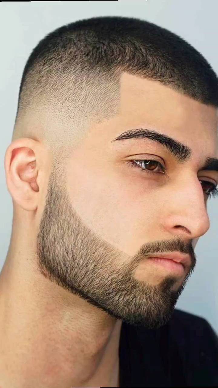 Man with a high skin fade buzz cut and a groomed full beard.