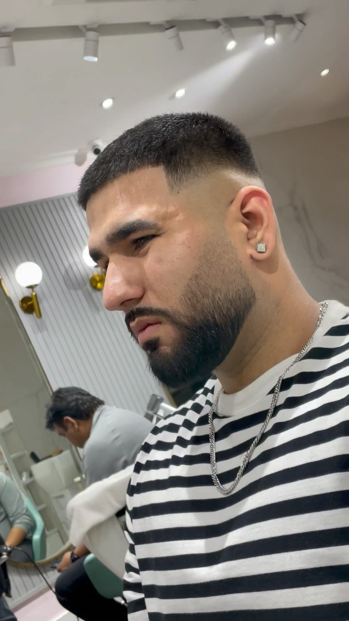 Man with a short crew cut and groomed beard in a barbershop setting.