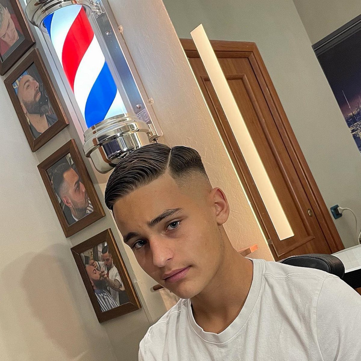 Young man with a neat side part hairstyle and faded sides in a barbershop.