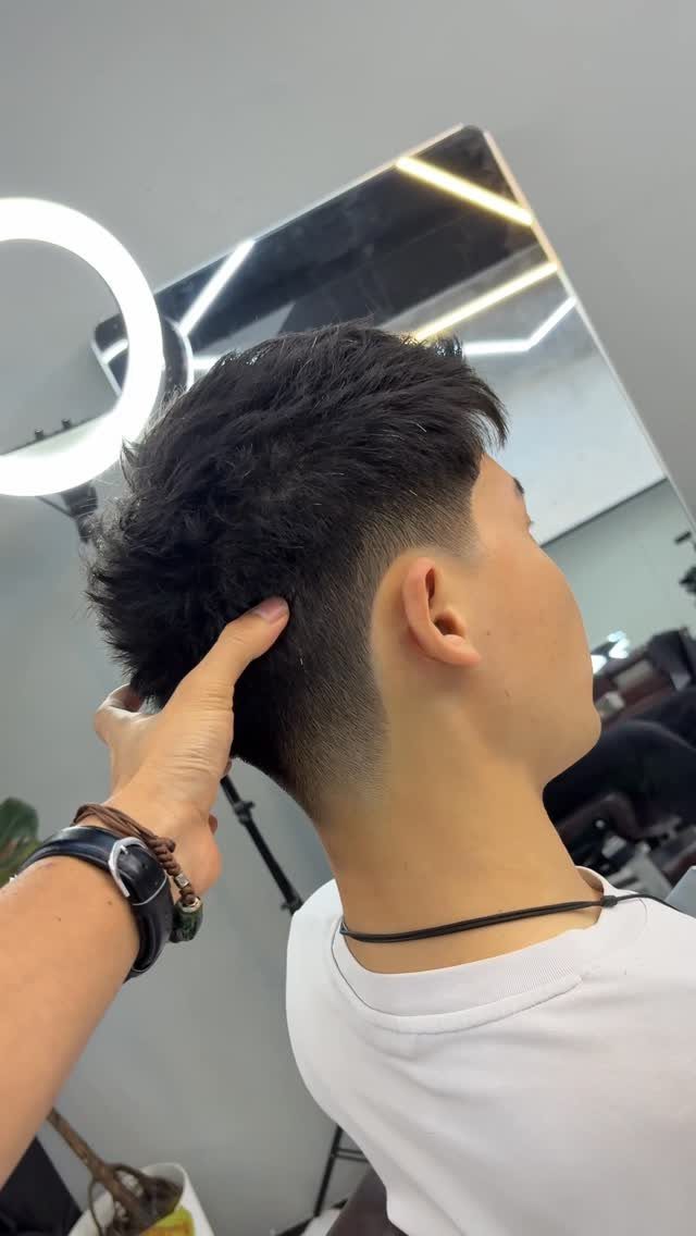Man with a short fade and textured top hair in a salon