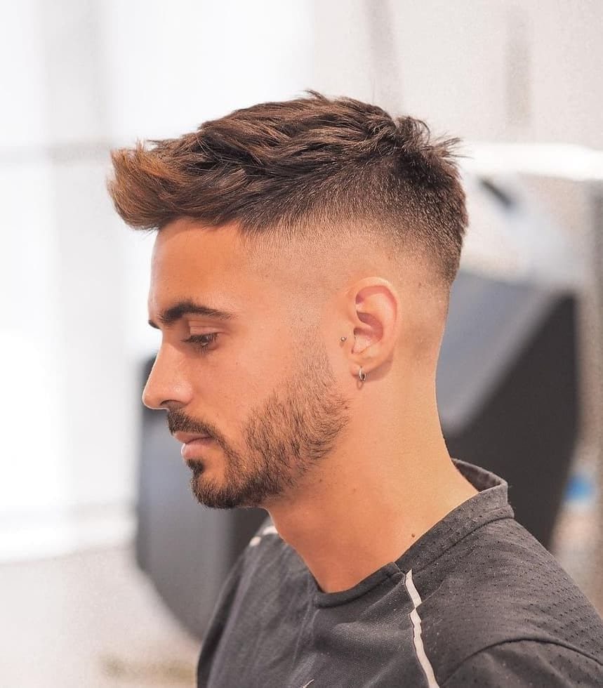 Man with a brown quiff hairstyle and faded sides in a side profile view