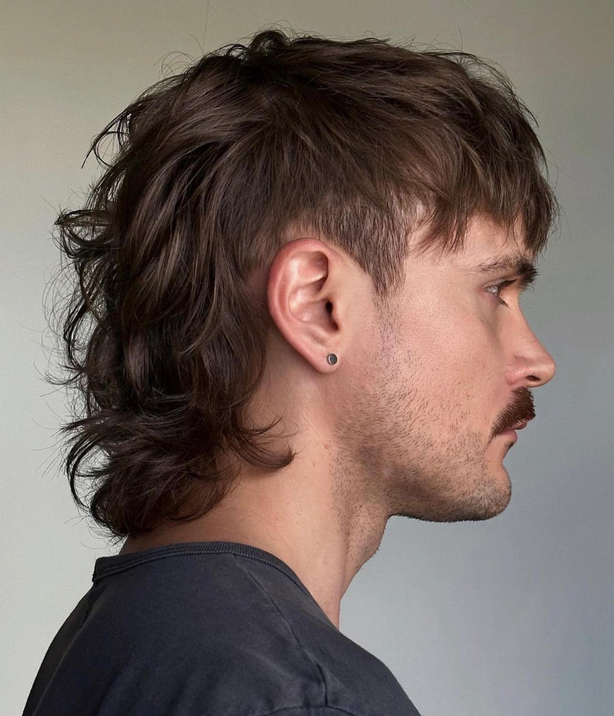 Man with a brown textured shag haircut featuring choppy layers and a soft fringe.