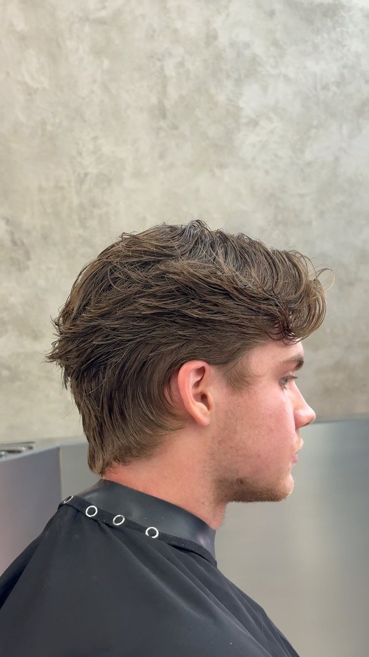 Young man with brown straight hair in a textured layered haircut side profile