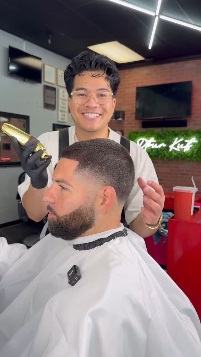 Man with a buzz cut and high fade being groomed by a barber.