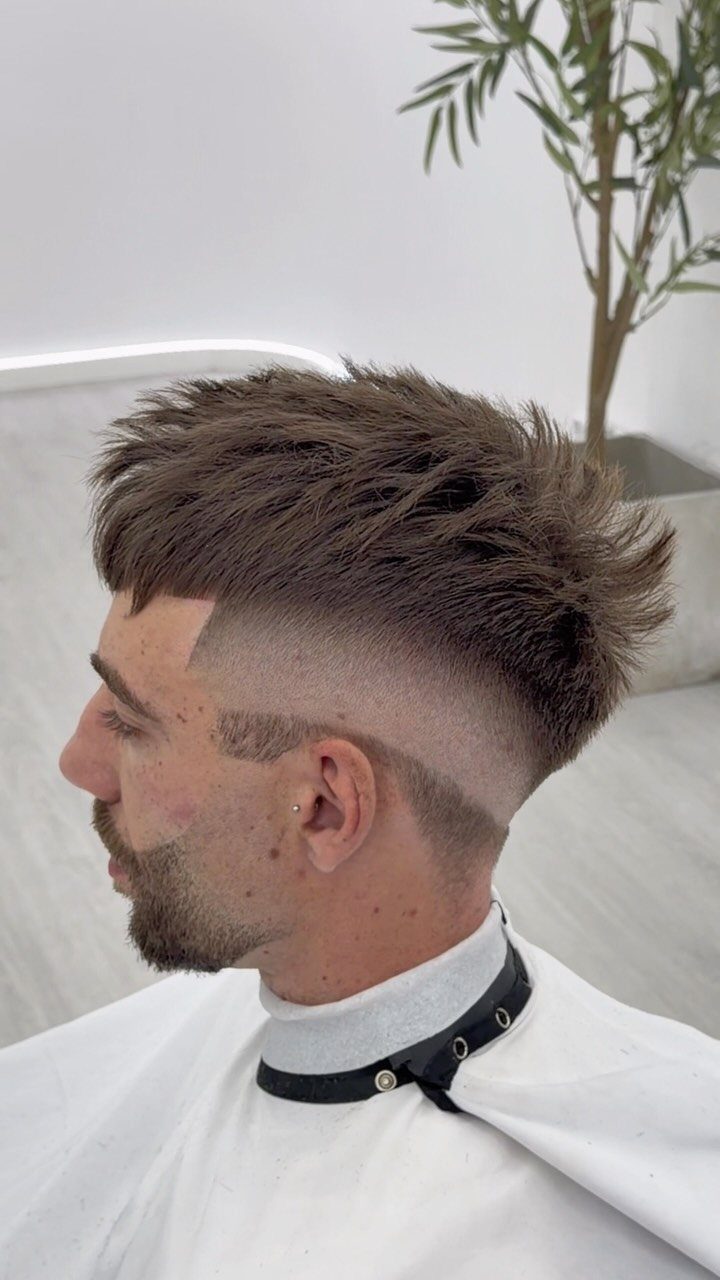 Man with a textured brown crop fade haircut and high skin fade sides.