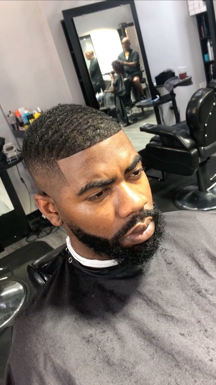 Man with a high skin fade haircut and a full groomed black beard.
