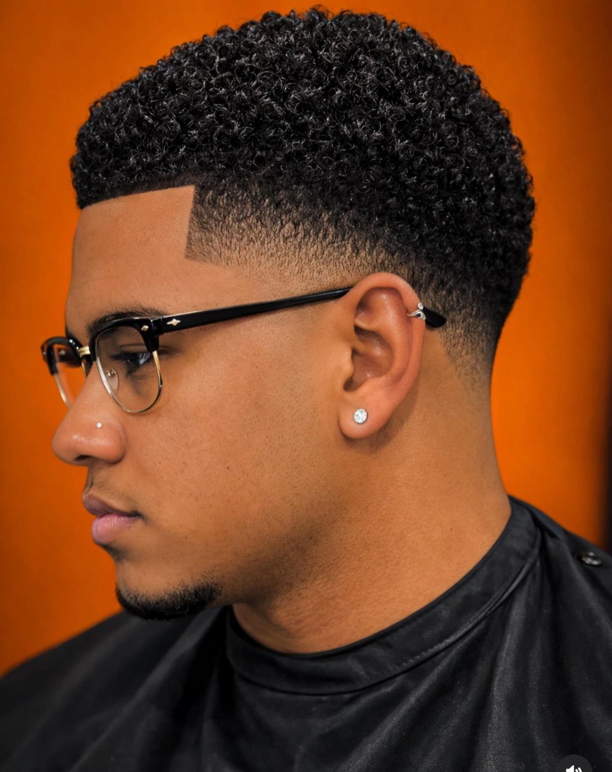 Man with a high fade haircut and tight curly hair on top.