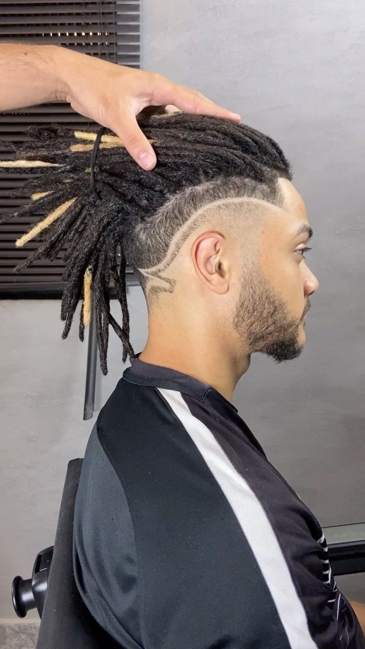 Man with high fade dreadlocks and a shaved design on the side of his head.