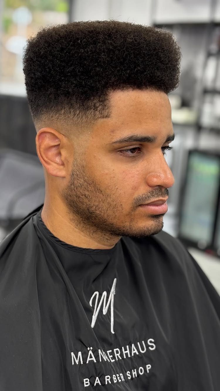 Man with a high fade haircut and flat top in a barber shop