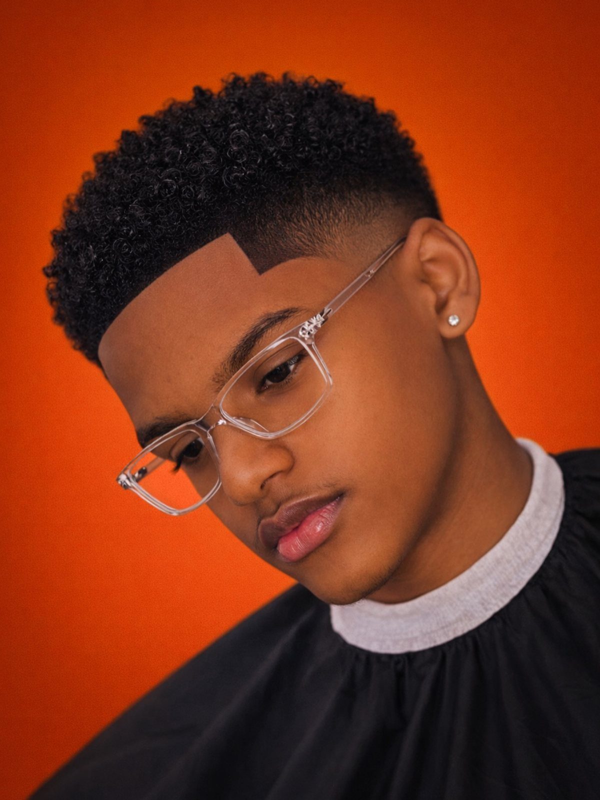 Young man with curly hair and a high fade haircut with sharp line-up.