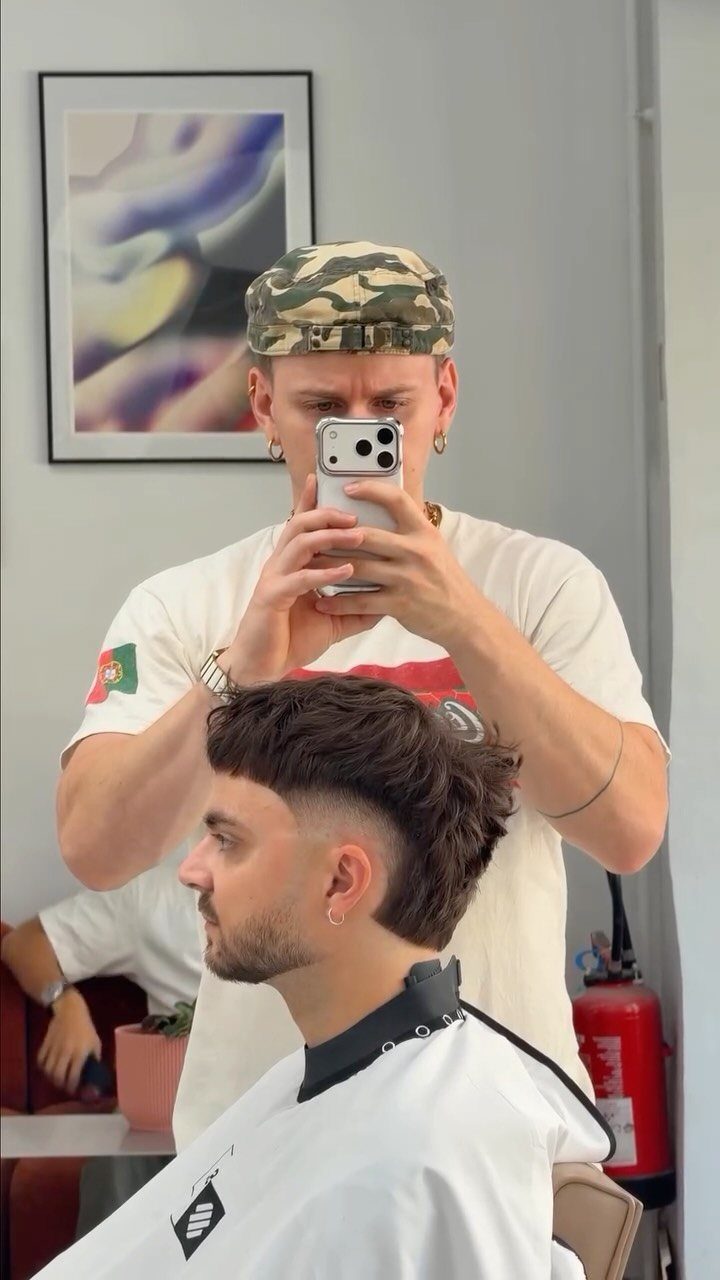 Man with a high fade haircut and long top in a barber shop.