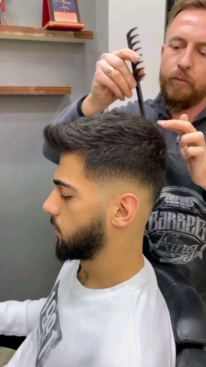 Man with a high fade quiff and beard getting his hair styled.