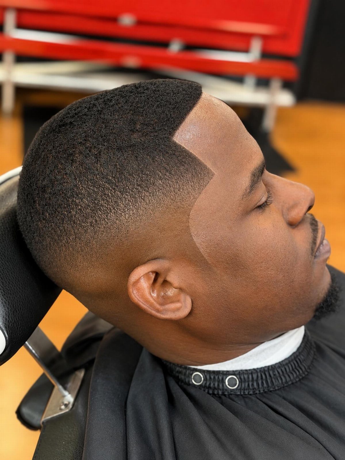 Man with a high shadow fade haircut and sharp line-up in a barbershop.
