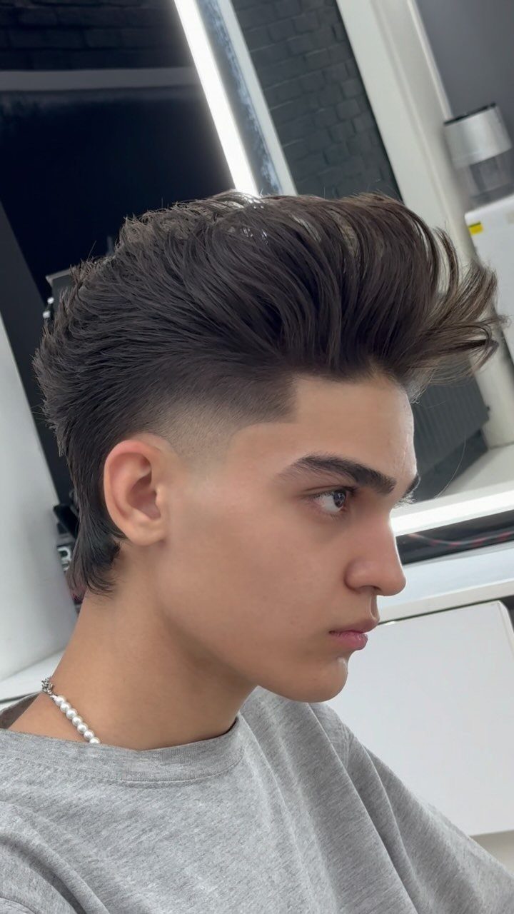 Young man with a high fade haircut and a voluminous swept-up pompadour style.