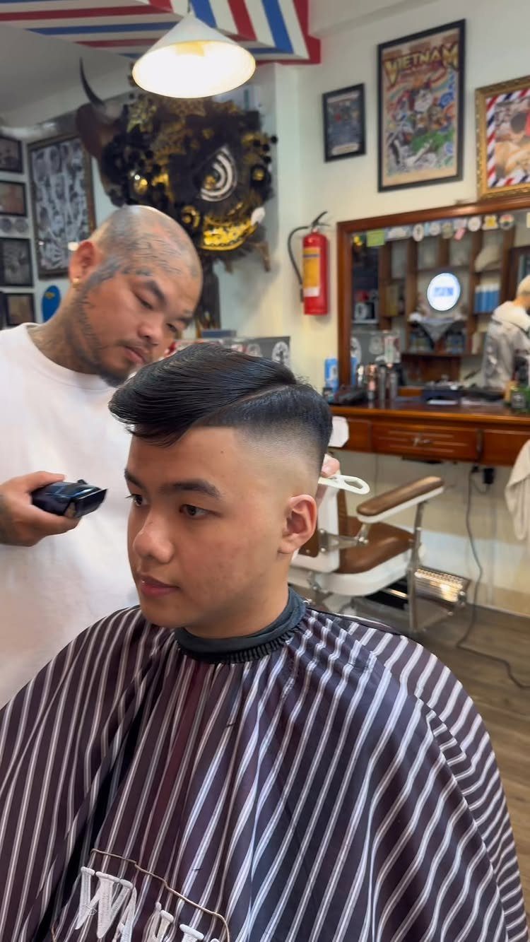 Barber cutting a man's hair into a high skin fade in a barbershop.
