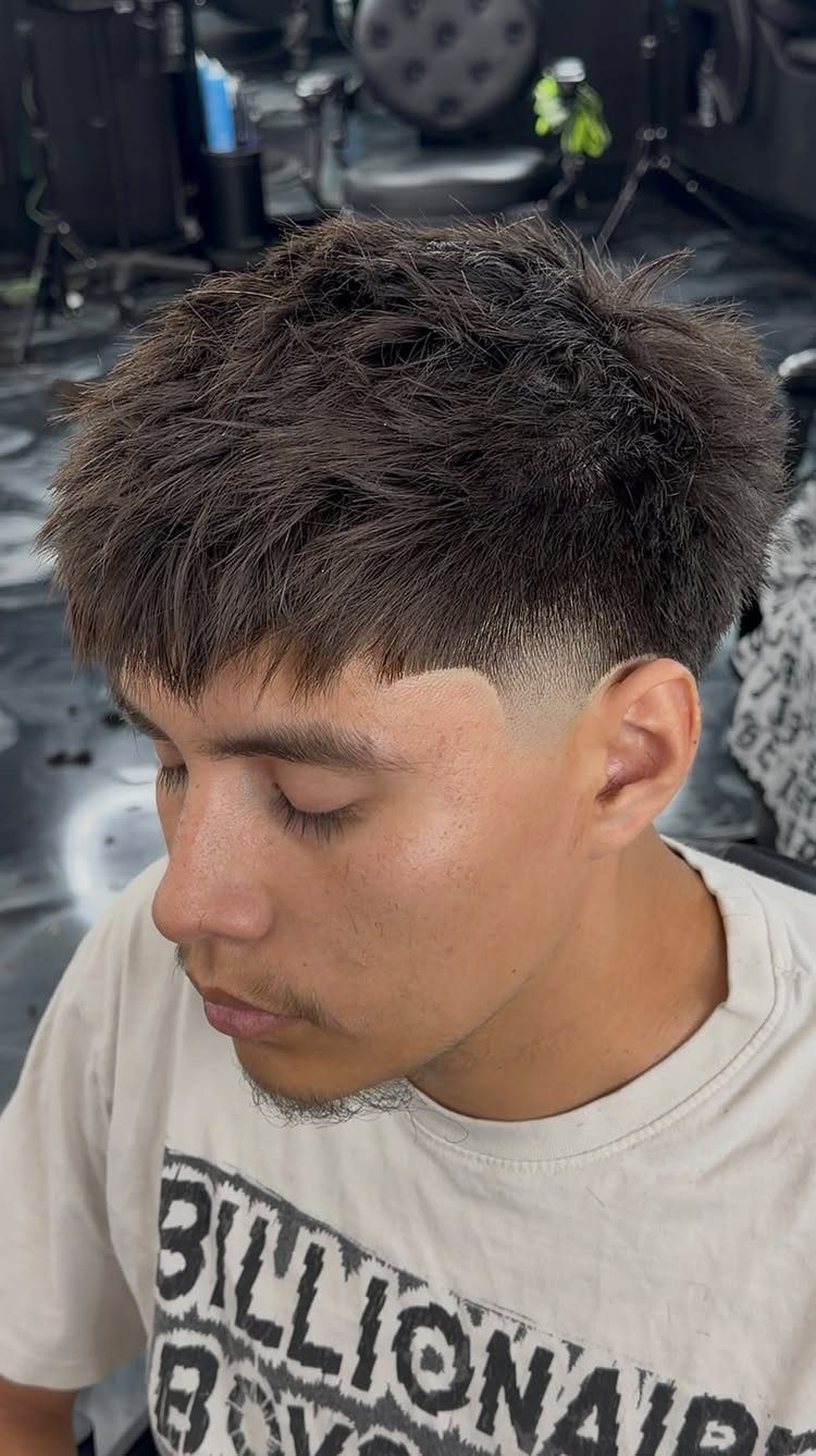 Young man with a high fade haircut and textured top in a barbershop.
