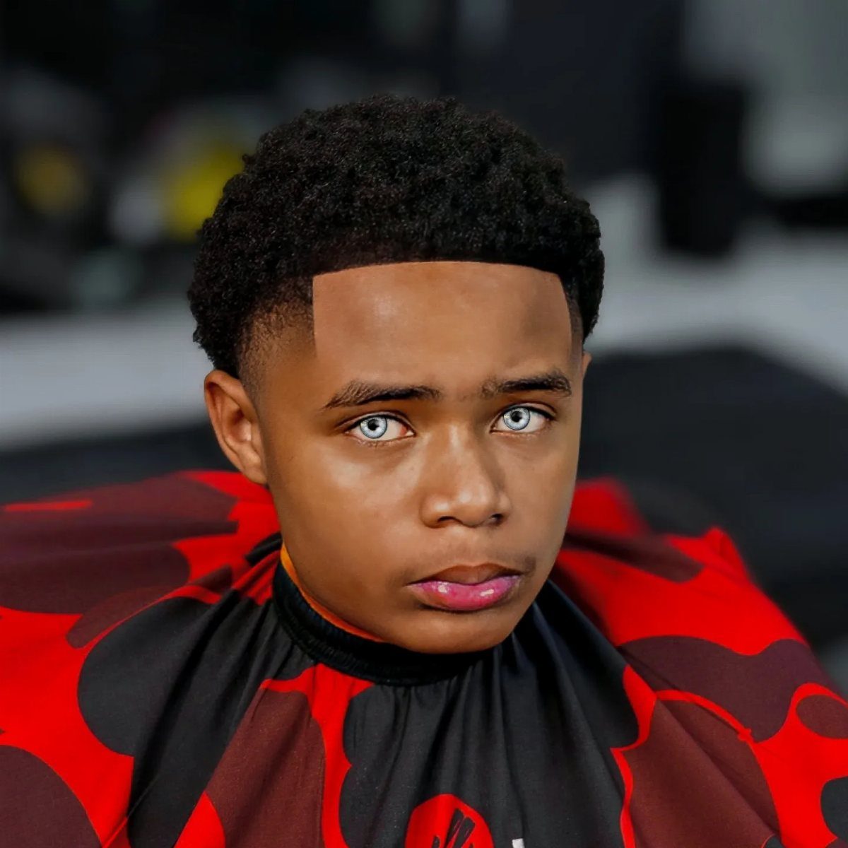Young man with a high taper fade and short curly afro hair.