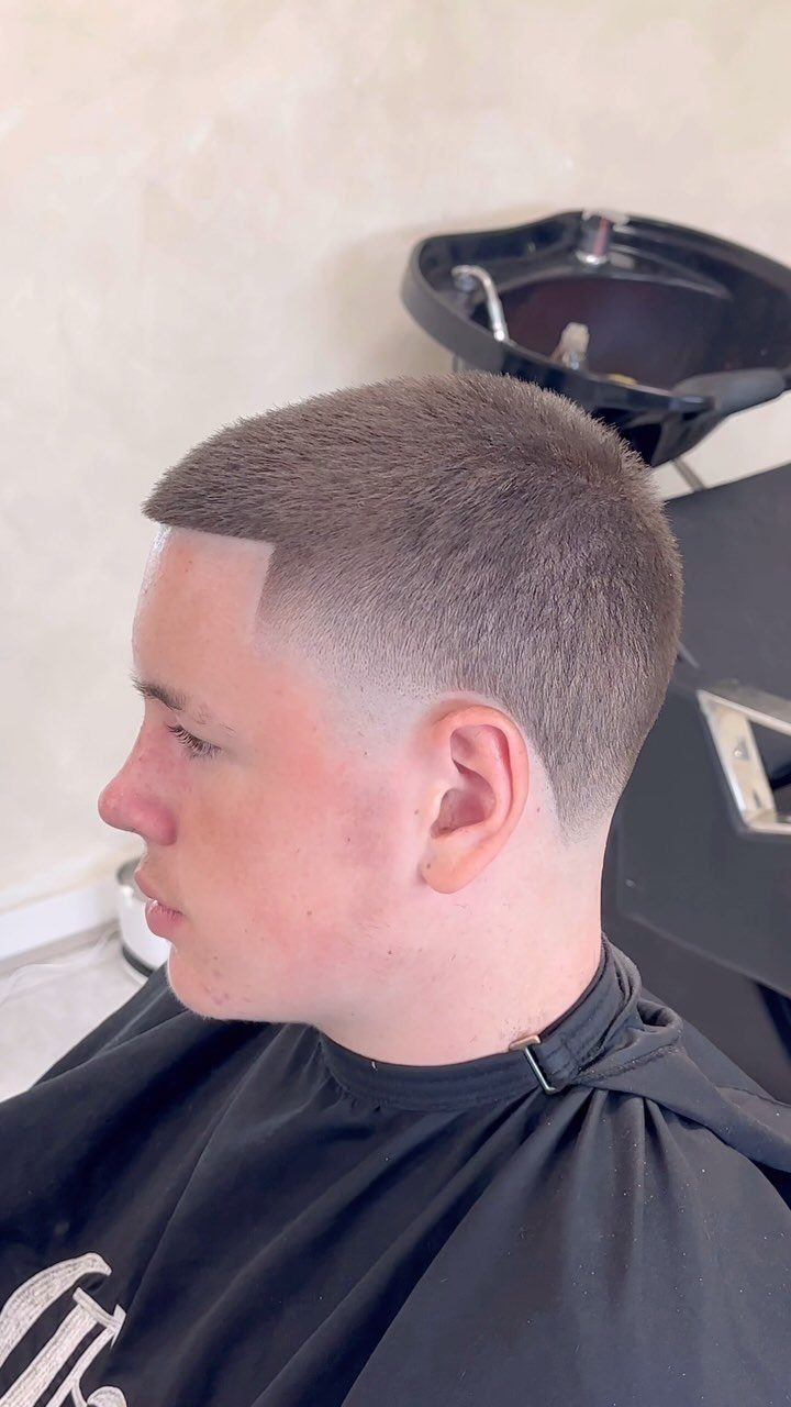 Man with a short buzz cut and high skin fade in a barbershop.