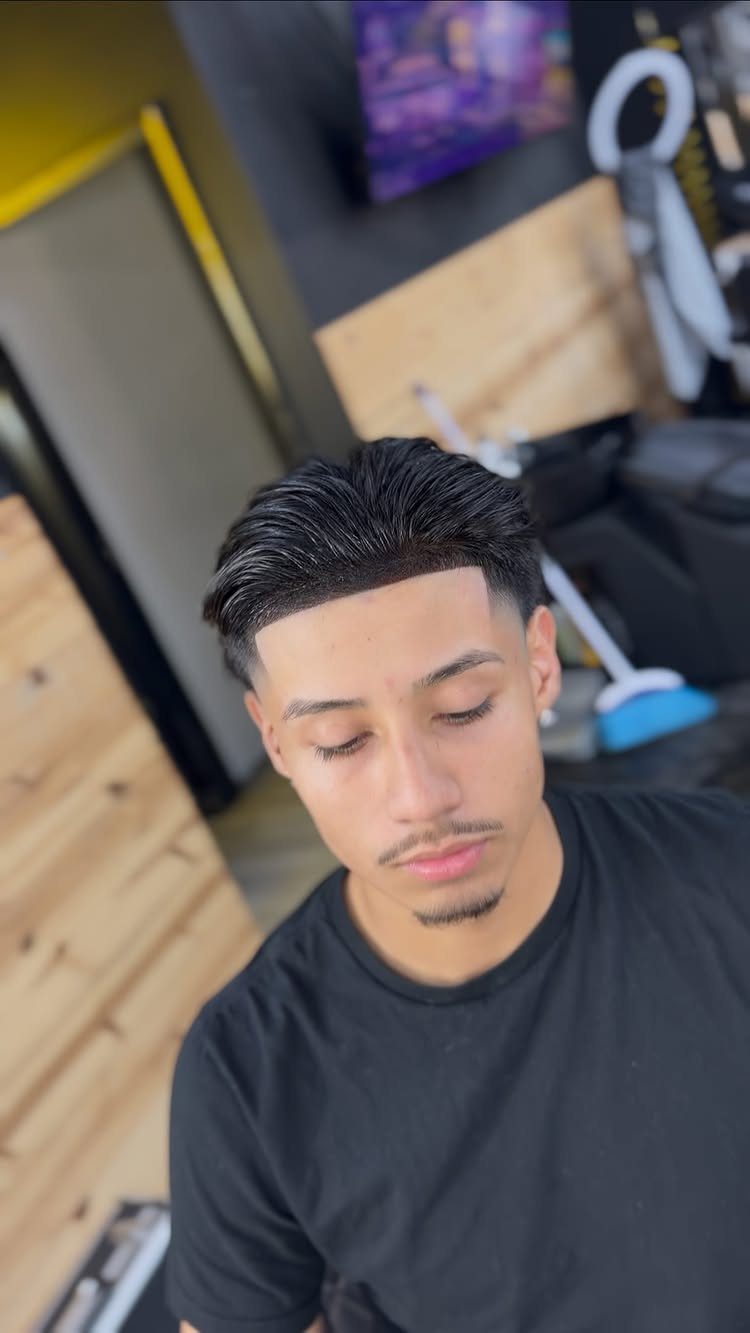 Young man with a high taper fade haircut and sharp line-up in a barbershop.