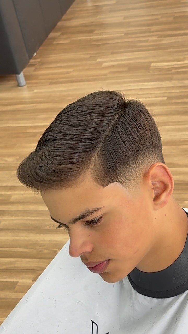 Young man with a high taper fade and a sharp side part hairstyle.