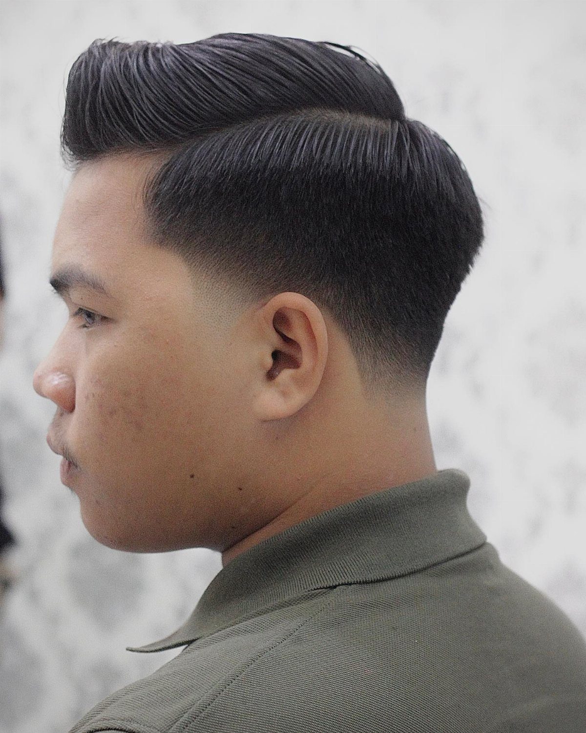 Man with a high taper fade and side swept top hairstyle in profile