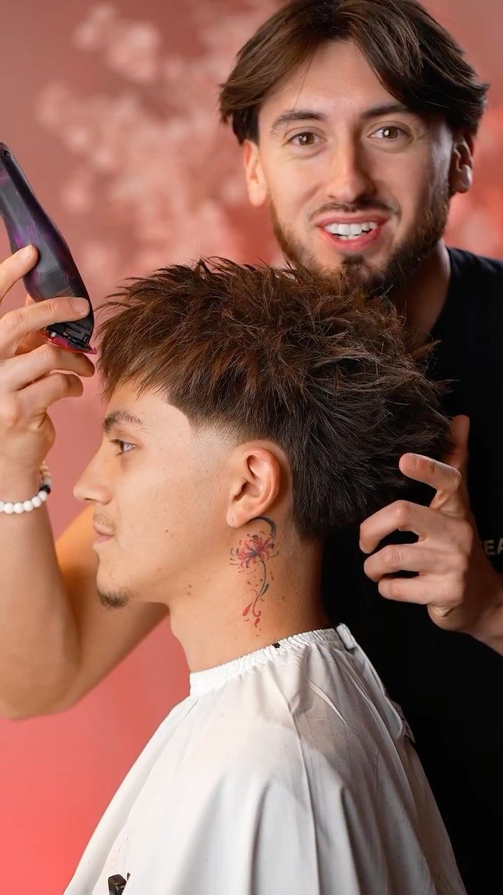 Man with a high taper fade and spiky top hair being styled by a barber.