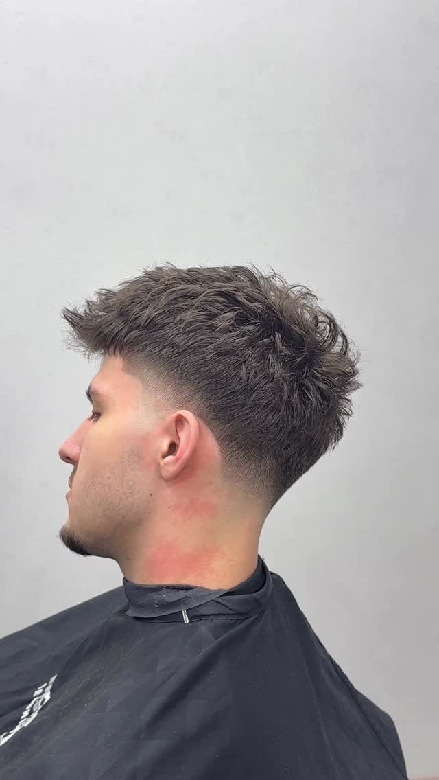 Man with a high taper fade haircut and wavy brown hair on top.