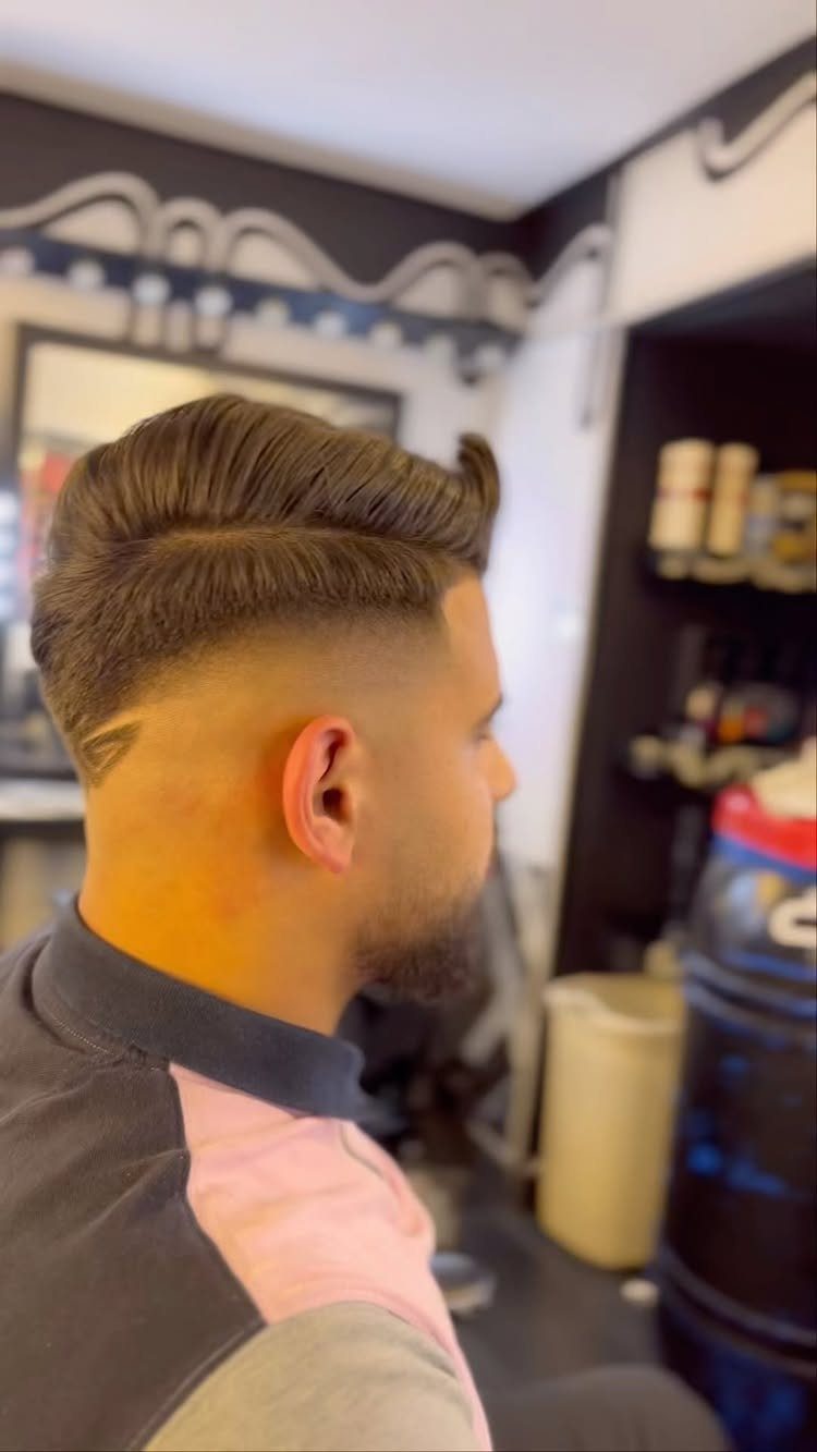 Man with a voluminous pompadour hairstyle and a high skin fade haircut.