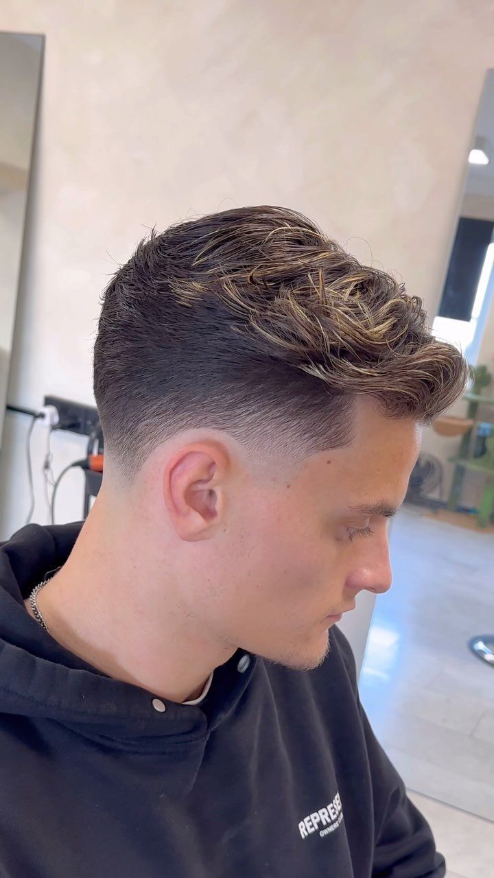 Man with a high taper fade and a voluminous styled quiff on top.