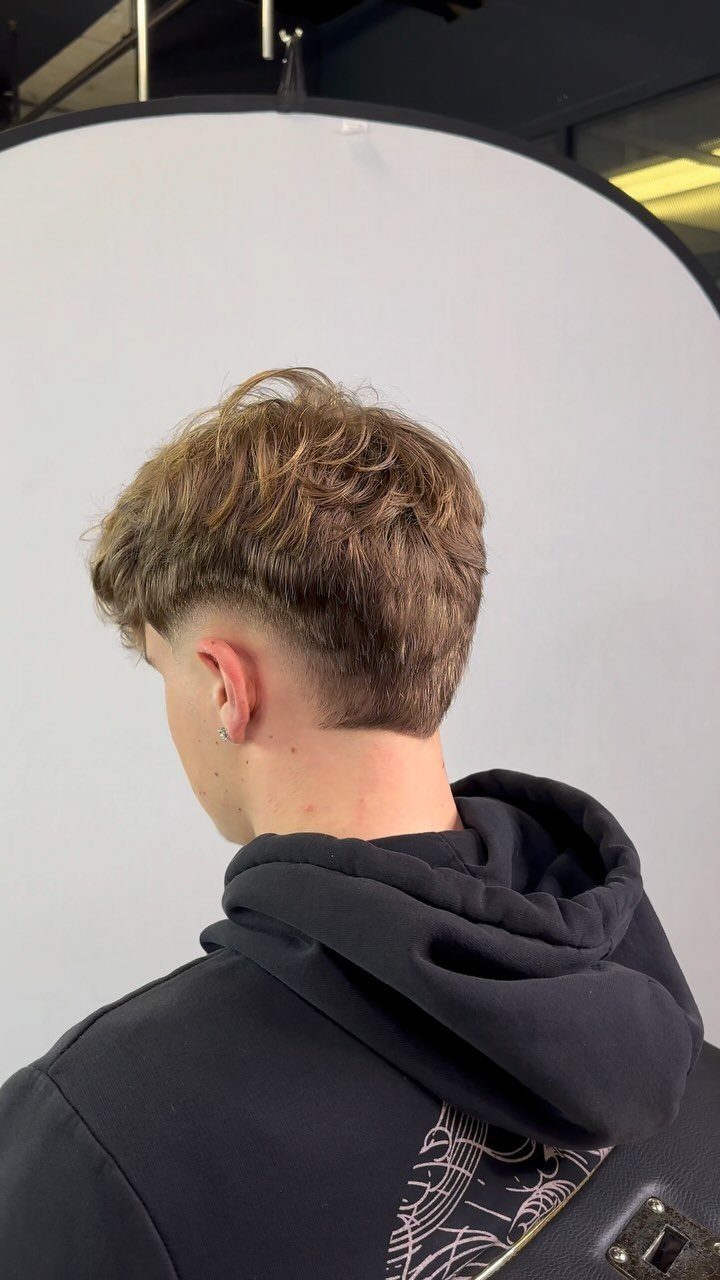 Man with a textured high taper fade haircut and choppy brown hair top.