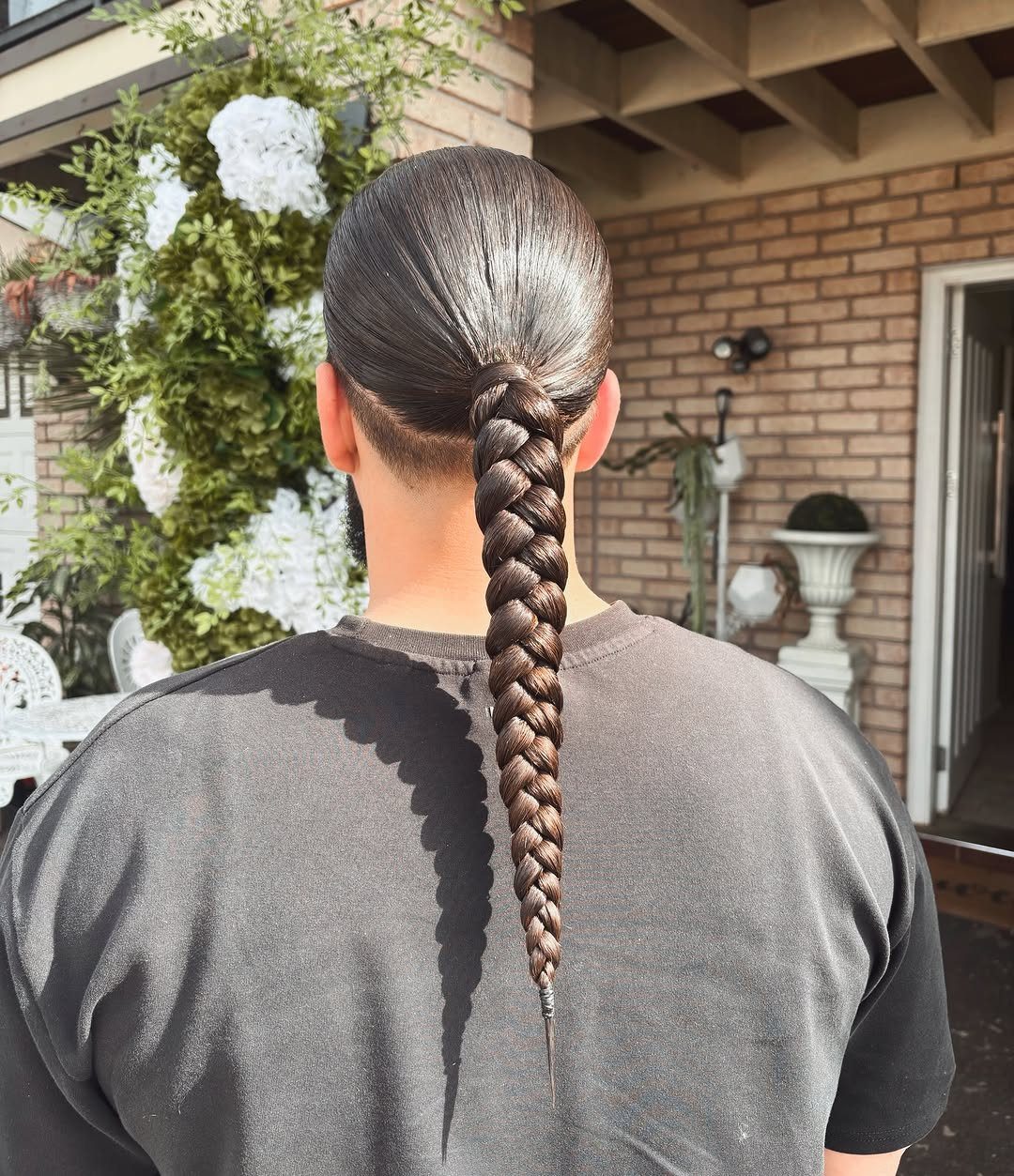 Man's long brown hair styled in a sleek ponytail and long thick braid.