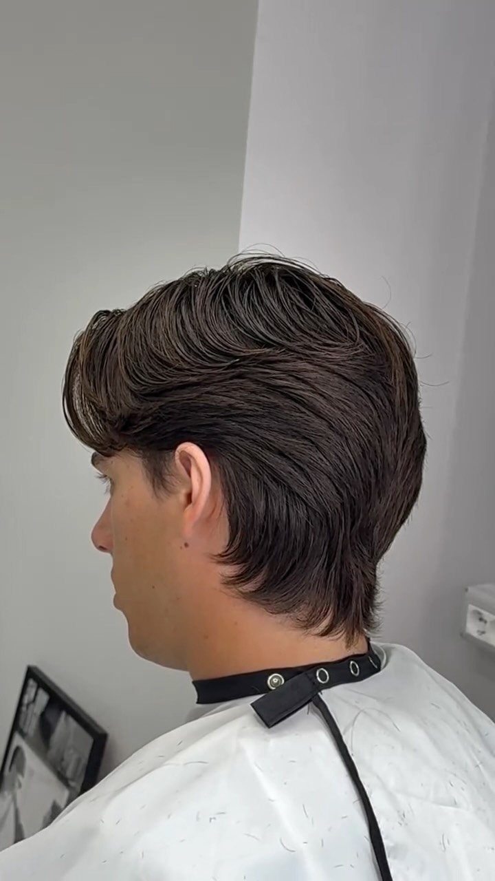 Man with medium-length brown hair styled in a bro flow with a side part.
