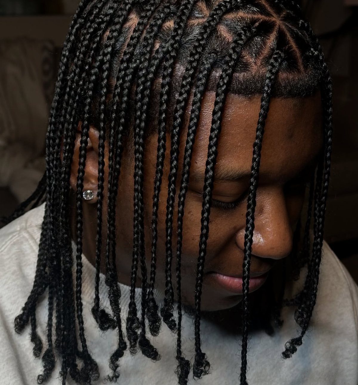 Person with long black hair styled in thin individual braids hanging down.
