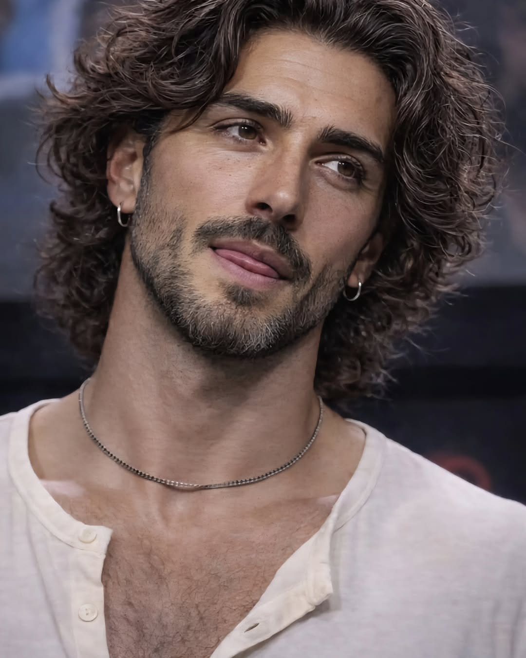 Man with long wavy brown hair and a groomed beard wearing a white shirt.