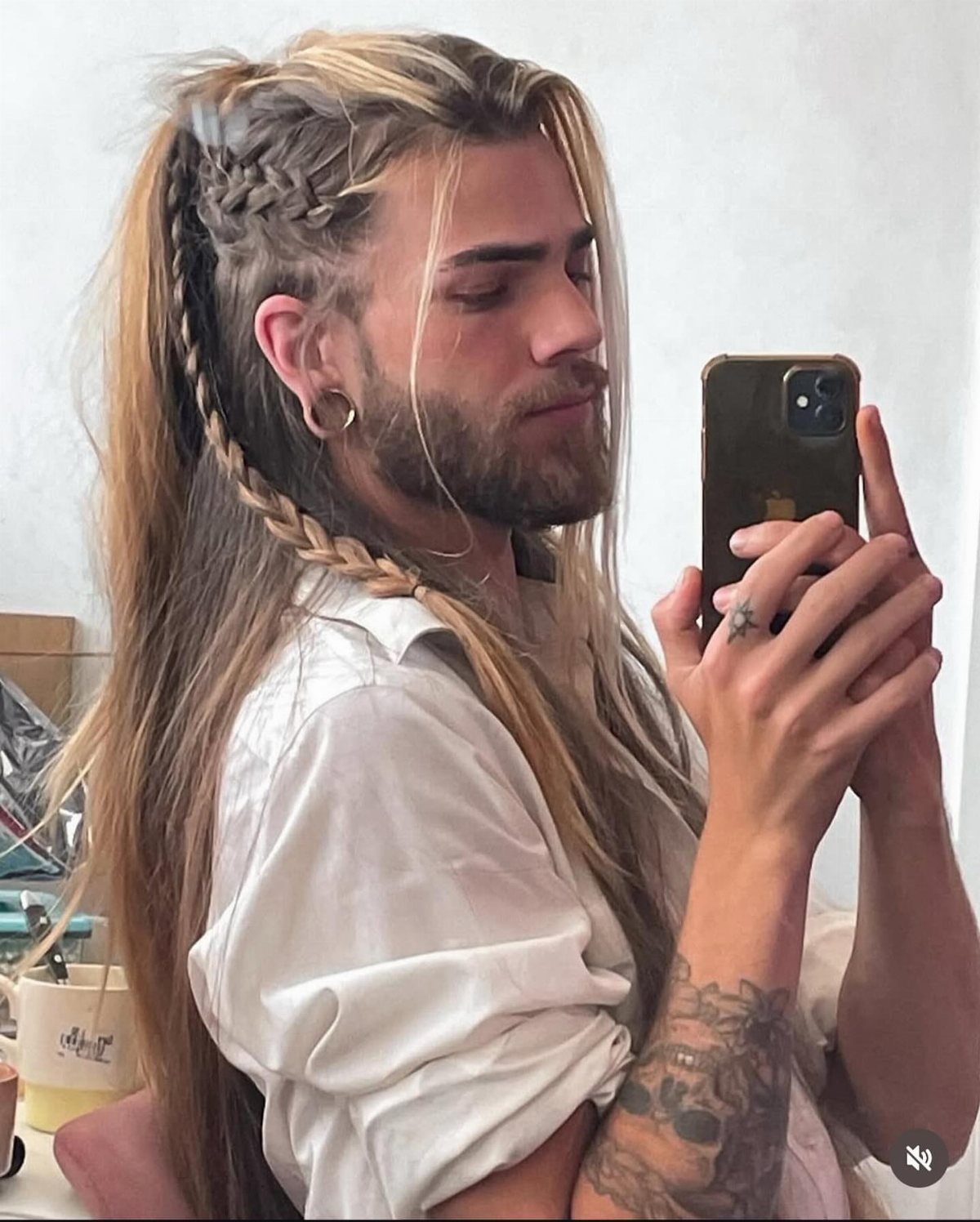 Man with long blonde hair, side braid, and beard taking a mirror selfie.
