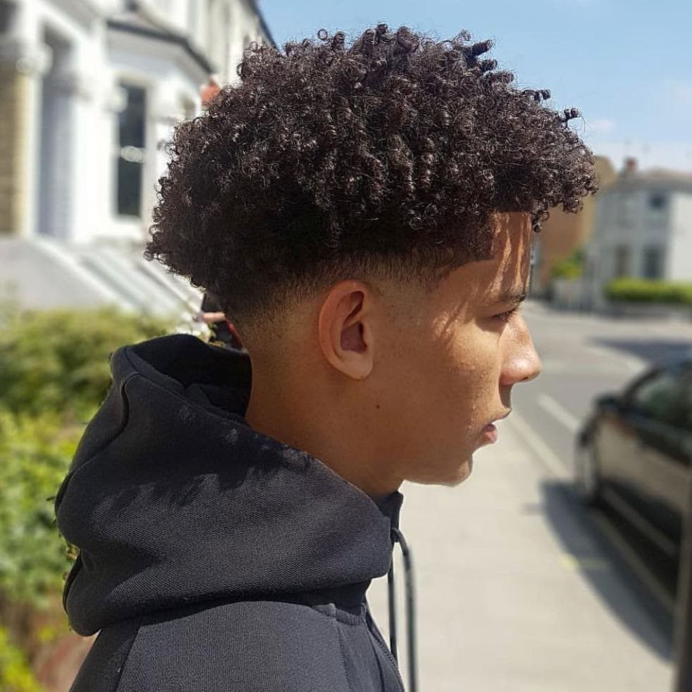 Young man with a voluminous curly afro top and a clean low fade haircut.